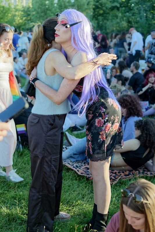 14 - A candid, joyful moment of two individuals embracing at a crowded outdoor Pride celebration